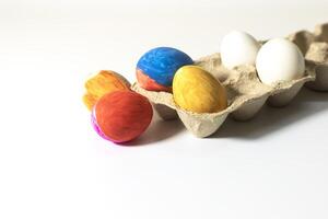 Colorful easter eggs in carton box on white background. Closeup photo