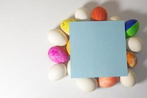 Colored easter eggs with blue card on white background photo