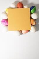 Easter eggs and yellow card on white background with copy space. photo