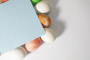 Easter eggs on a white background with a blue sheet of paper. Happy Easter concept. photo