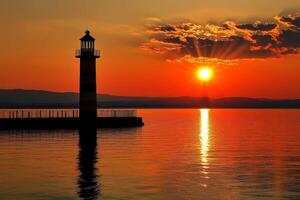 Lighthouse reflecting on calm water at sunset with sunrays photo