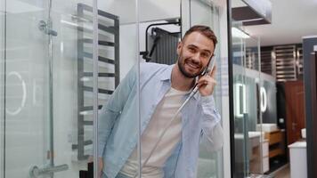 Funny man buyer imitates a phone call in shower cabin in plumbing store video
