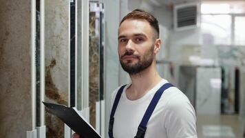 Portrait of seller in overalls with clipboard in hardware tile store. video