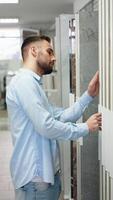 A handsome man choosing ceramic tile in domestic shop. Vertical video