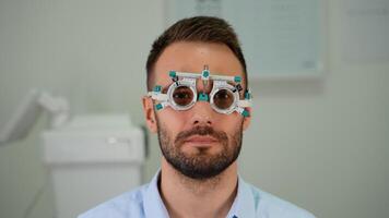 A man doing eyesight measurement with trial frame and visual test chart on white video