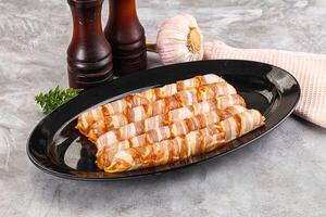 Raw sausages wrapped in bacon photo