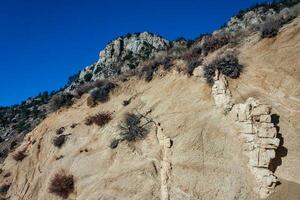 Conifers and other drought-resistant plants grow on the clay and stone rocks of the mountain at the pass in the Sierra Nevada Mountains, California, USA photo