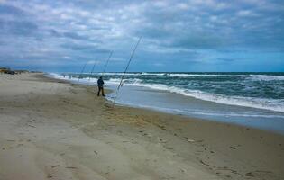 New Jersey, USA - November 19, 2009 Fishermen on the sandy shore of the Atlantic Ocean in New Jersey, USA photo
