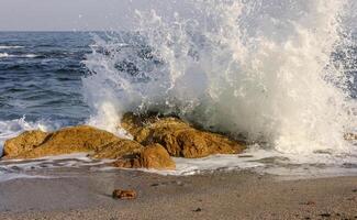 Waves break on a stone and white splashes of water fly into the air, the Black Sea photo