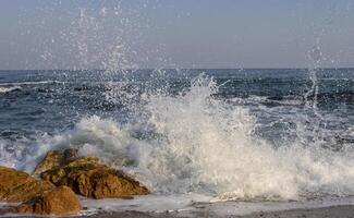 Waves break on a stone and white splashes of water fly into the air, the Black Sea photo