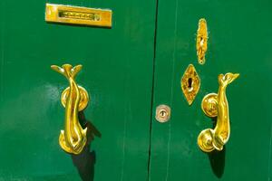 Traditional handle and doorknocker made of brass in the form of fish on the doors of old houses in Malta photo