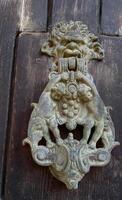 Traditional copper handle and door knocker on wooden doors of old houses in Malta, Gozo photo