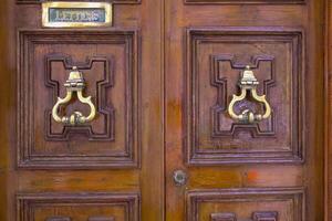 Traditional copper handle and door knocker on wooden doors of old houses in Malta photo