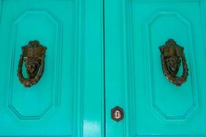 Traditional copper handle and door knocker on wooden doors of old houses in Malta photo