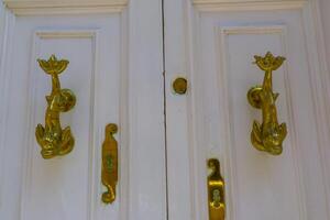 Traditional copper handle and door knocker on wooden doors of old houses in Malta photo
