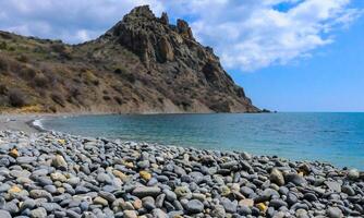 Kara-Dag, volcanic rocks near the Black Sea coast in the national park, rounded pebbles on the beach, Crimea photo