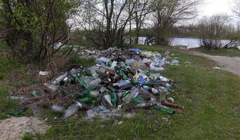 Environmental problem, pollution, polyethylene, polypropylene, mud, waste, scrap metal, bottles, garbage dump on the river bank photo