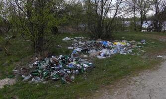 Environmental problem, pollution, polyethylene, polypropylene, mud, waste, scrap metal, bottles, garbage dump on the river bank photo
