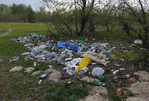 Environmental problem, pollution, polyethylene, polypropylene, mud, waste, scrap metal, bottles, garbage dump on the river bank photo
