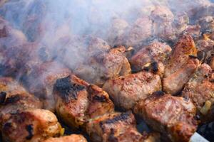 Pork meat is fried on smoking coals in the grill photo