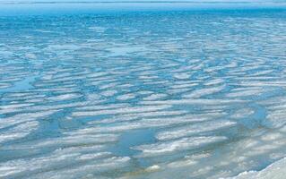 Ice floating near the shore in the form of oblong ice floes, rolled around by waves and a storm in the Tiligul estuary photo