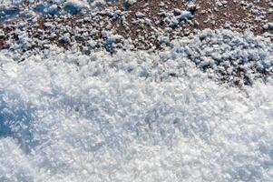 Weathered ice and frozen snow in the form of needle crystals on the bank of the Tiligul Estuary on a sunny day photo
