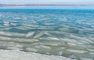 Ice floating near the shore in the form of oblong ice floes, rolled around by waves and a storm in the Tiligul estuary photo