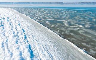 Ice floating near the shore in the form of oblong ice floes, rolled around by waves and a storm in the Tiligul estuary photo