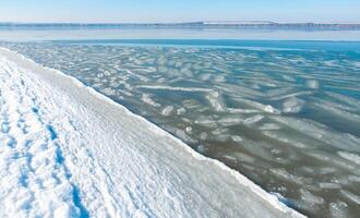 Ice floating near the shore in the form of oblong ice floes, rolled around by waves and a storm in the Tiligul estuary photo