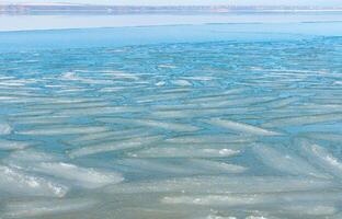 Ice floating near the shore in the form of oblong ice floes, rolled around by waves and a storm in the Tiligul estuary photo