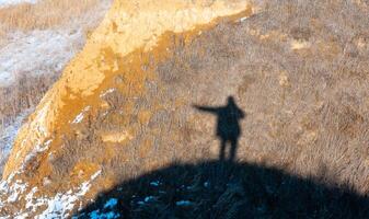 Black shadow, silhouette of a man with a raised hand on the shore of the estuary in winter photo