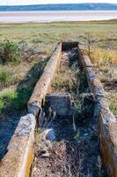 Old abandoned drinking bowls for grazing animals on the shore photo