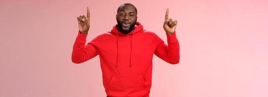 Arrogant young bragging handsome cheeky african-american bearded guy pointing raised index finger up smirking look assertive self-assured, recommending amazing product, pink background photo
