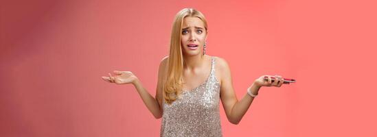 Frustrated upset dumped blond attractive girlfriend shrugging hands sideways dismay look questioned cocnerned clueless why break-up via message holding smartphone grimacing perplexed photo
