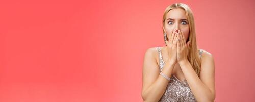 Concerned shocked worried blond woman terrified gasping cover mouth hands pray gesture widen eyes witness terrible accident worry expressing empathy pity, standing red background uneasy photo