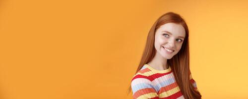 Silly flirty good-looking redhead girl making first move checking out guy standing profile turning left smiling intrigued glancing aside coquettish flirting seducing sassy, orange background photo