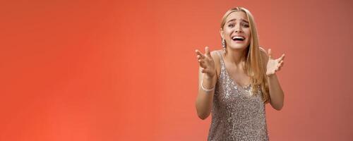 Panicking upset miserable heartbroken blond girl crying raising hands begging not go broke-up boyfriend look sorrow distressed freak-out standing devastated red background during party photo
