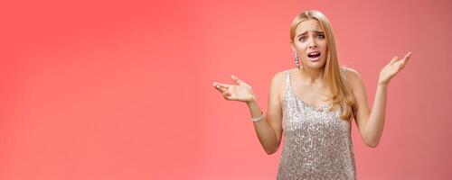 Why leaving early. Upset complaining young attracitve bothered blond woman complaining look questioned disappointed raise hands up sideways dismay clueless frowning displeased, red background photo