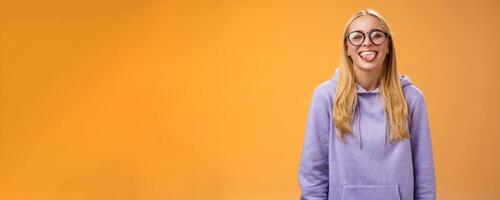Funny charming female programmer having fun show tongue fool around coworkers during lunch break smiling broadly laughing in cute glasses purple hoodie, standing purple background photo