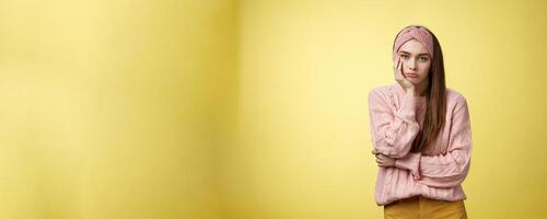 How boring. Indifferent upset gloomy girl missing party feeling bored leaning on palm reluctant, sad looking careless at camera visiting uninteresting lecture, suffering boredom over yellow wall photo