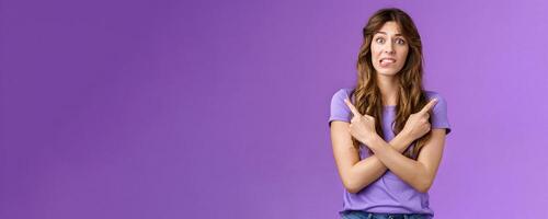 Perplexed timid hesitant worried girlfriend afraid making bad choice cross hands pointing sideways indicating left right perplexed decide frowning pull hesitant face asking advice purple background photo