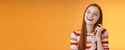 Silly good-looking flirty lively redhead young girl laughing playing coquettish ginger hair strand chuckling amused funny boyfriend jokes having fun awesome romantic date, orange background photo