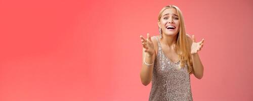 Panicking upset miserable heartbroken blond girl crying raising hands begging not go broke-up boyfriend look sorrow distressed freak-out standing devastated red background during party photo