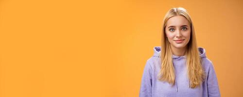 Waist-up delicate tender friendly-looking blond european girl in hoodie smiling supportive talking listening friends story nice interesting conversation standing casually orange background photo