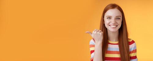 Girl pointing left cool person can help smiling delighted look friendly camera discuss interesting project introduce friend during conversation standing happy grinning orange background photo