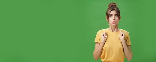 Studio shot of silly insecure and timid young wife feeling troubled and concerned, pressing hands to body folding lips and frowning looking scared and nervous facing troublesome situation, worry photo