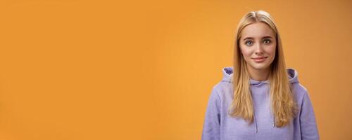 Waist-up delicate tender friendly-looking blond european girl in hoodie smiling supportive talking listening friends story nice interesting conversation standing casually orange background photo