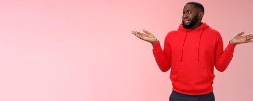 African american man cringe shake head unaware frowning grimacing aversion dislike shrugging hands raised sideways have no idea, standing dissatisfied unpleasant question, clueless pink background photo