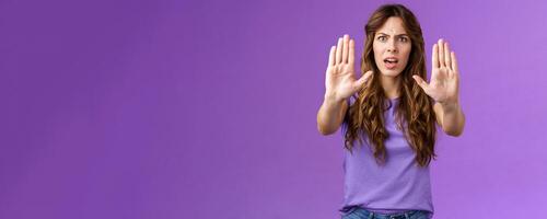 You need stop hold it. Serious-looking intense displeased woman pull hands prohibition taboo sign frowning demand enough shooting me bad mood restict doing mistake purple background photo
