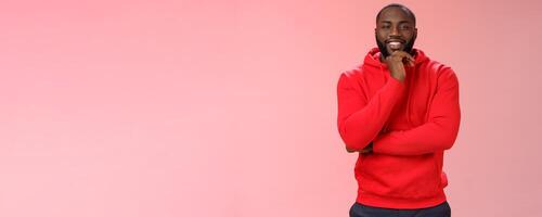 Curious delighted african-american young creative guy thinking new business plan smiling pleased have interesting suggestion rubbing chin thoughtful grinning cross arm chest listening intrigued photo